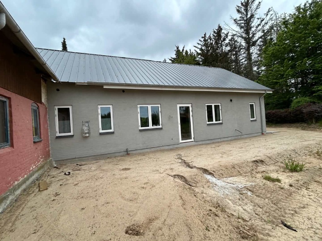 Grå vandskuret facade med hvide vinduer